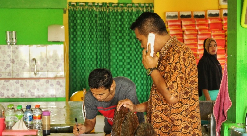 Wajib Pajak yang memiliki usaha rumah makan sedang menandatangani tanda terima undangan