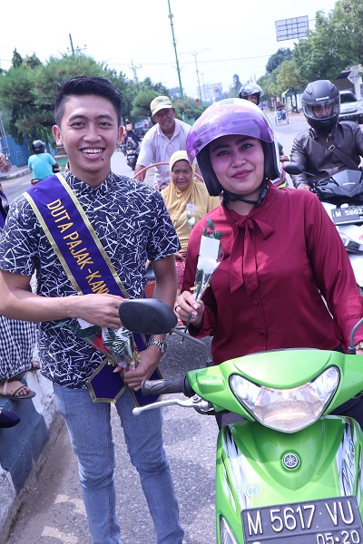 Duta Pajak membagikan bunga kepada pengendara motor