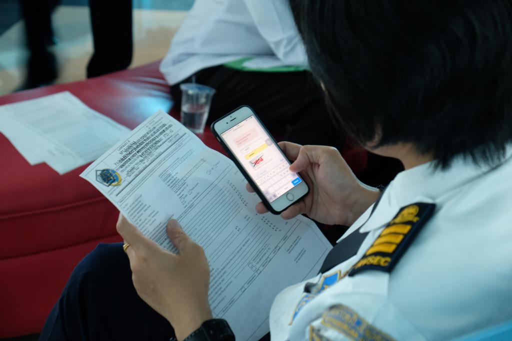 Petugas bandara mengakses situs djponline.pajak.go.id menggunakan ponsel.