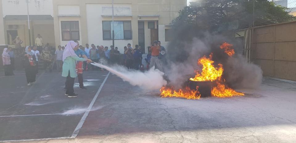 Pegawai perempuan ikut mencoba menggunakan APAR untuk memadamkan api.