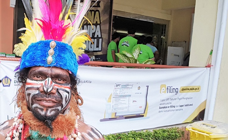 Seorang penari Papua berfoto dengan latar spanduk e-Filing