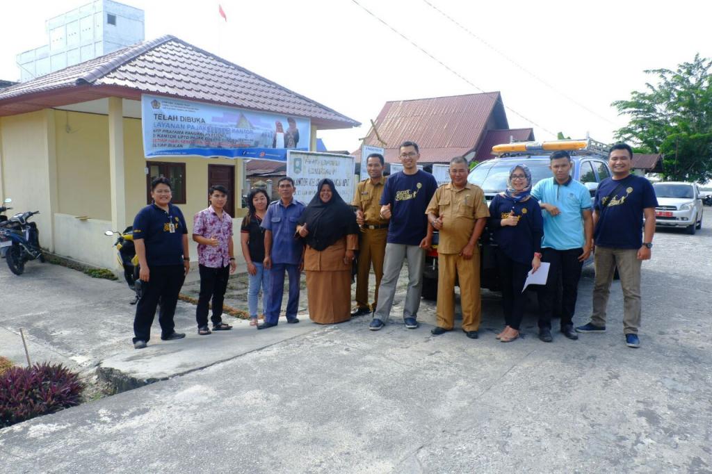 Berfoto bersama perangkat desa dan wajib pajak dengan latar belakang mobil pajak
