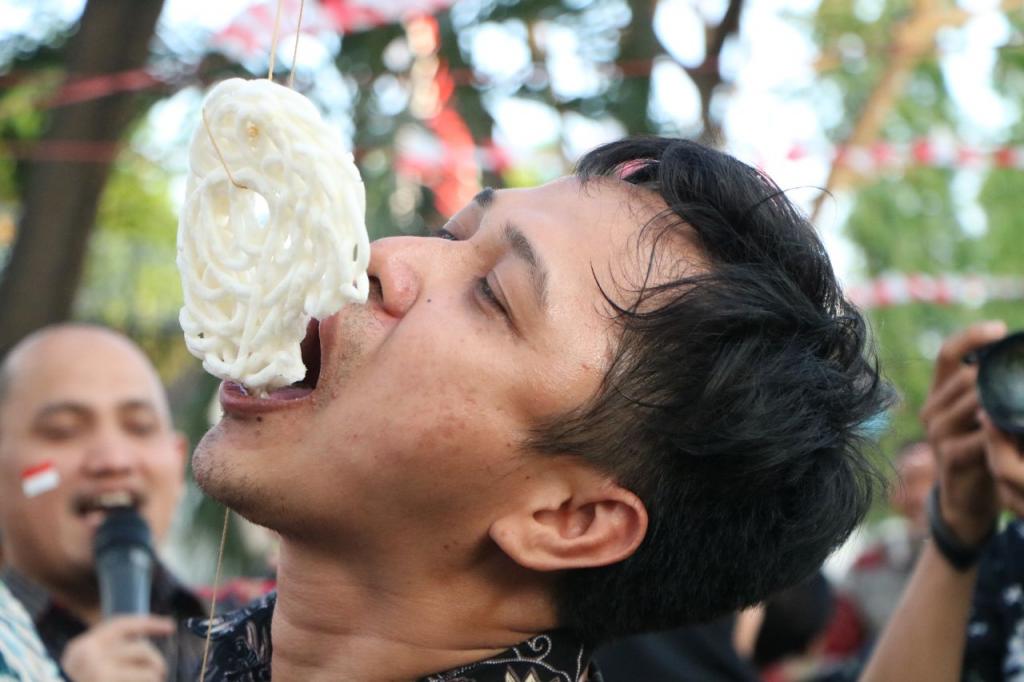 Kaki terikat, tinggi kerupuk menyesuaikan kaki yang harus diangkat, peserta lahap menyantap kerupuk