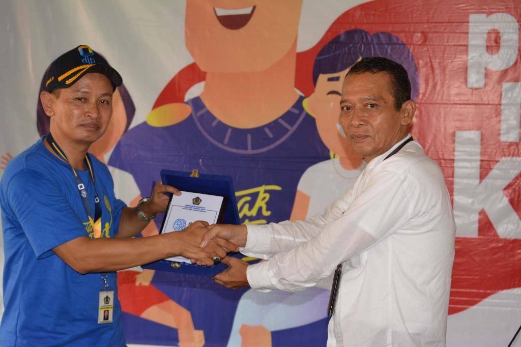 Pemberian plakat kegiatan Pajak Bertutur oleh ketua tim Pajak Bertutur KPP Pratama jakarta Tambora oleh Rahmat Prihantoyo