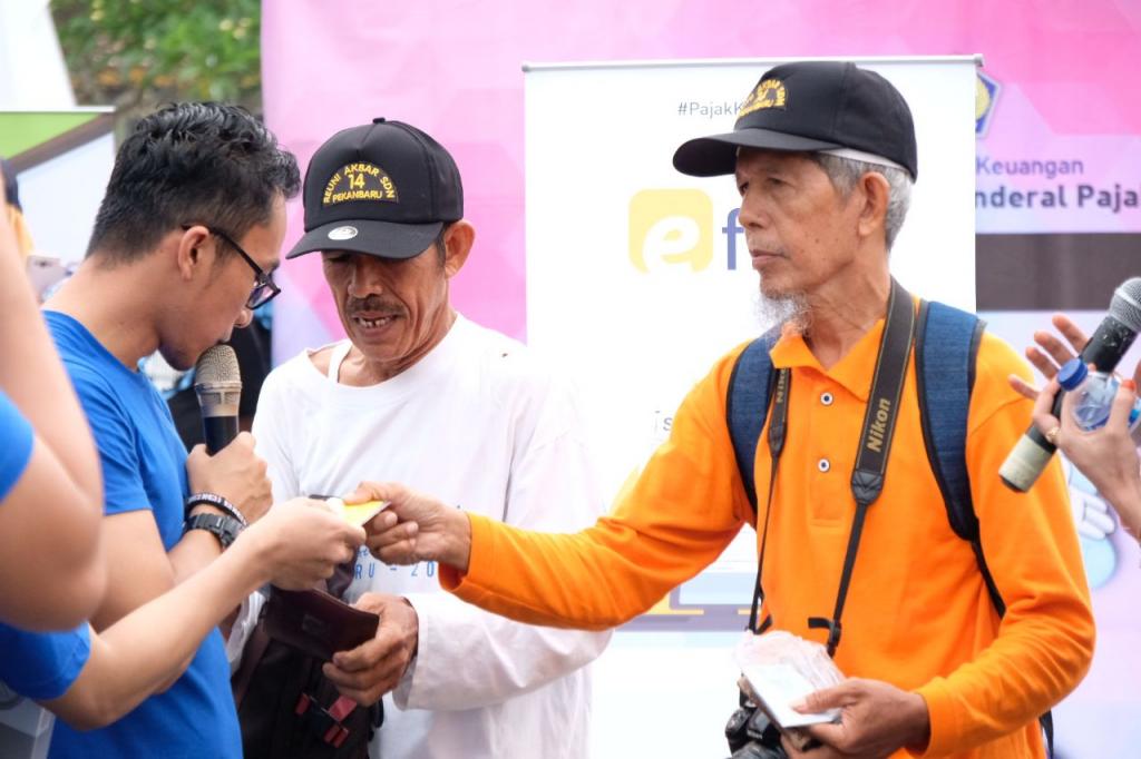 Pensiunan pegawai menunjukkan kartu NPWP-nya sebelum mendapat hadiah dari pegawai