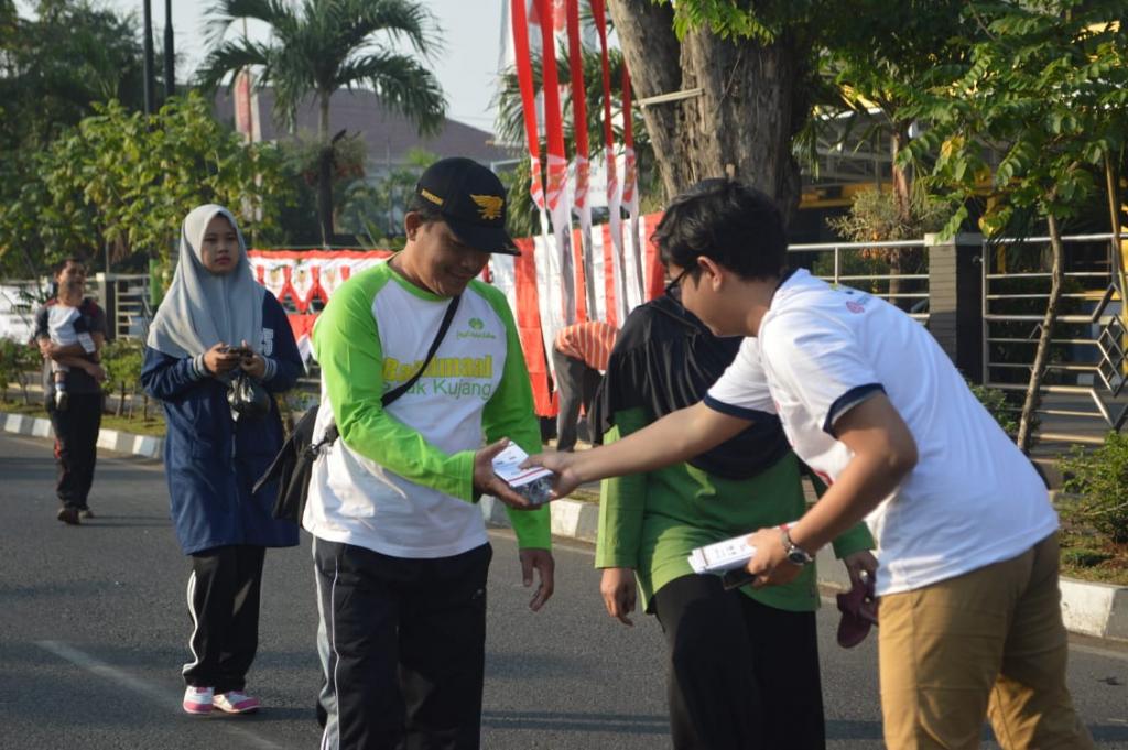 Pegawai KPP Karawang Utara membagikan Leaflet PP 23 Tahun 2018 Penurunan Tarif Pajak UMKM kepada masyarakat yang berolahraga pada Car Free Day Karawang