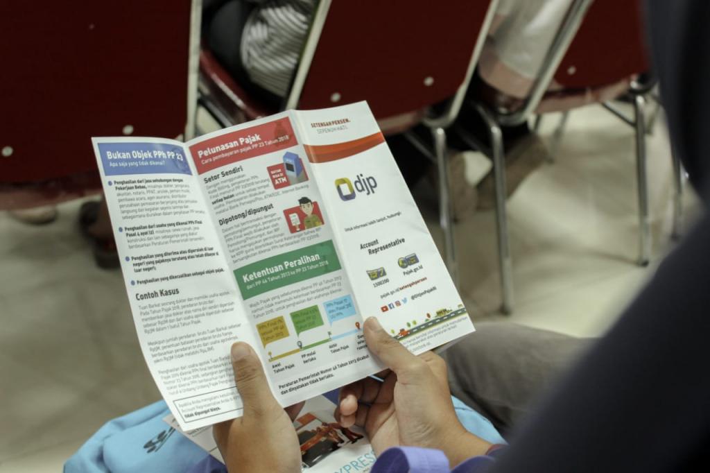 Peserta sedang mempelajari PP 23 Tahun 2018 dari leaflet yang diberikan