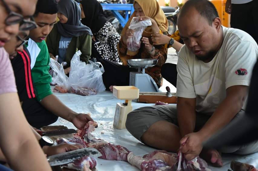 Tampak salah satu pegawai sedang membantu memotong daging qurban