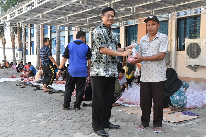 Kepala KPP Pratama Pamekasan, Teddy Hariyanto sedang membagikan daging qurbak kepada salah satu yang berhak.